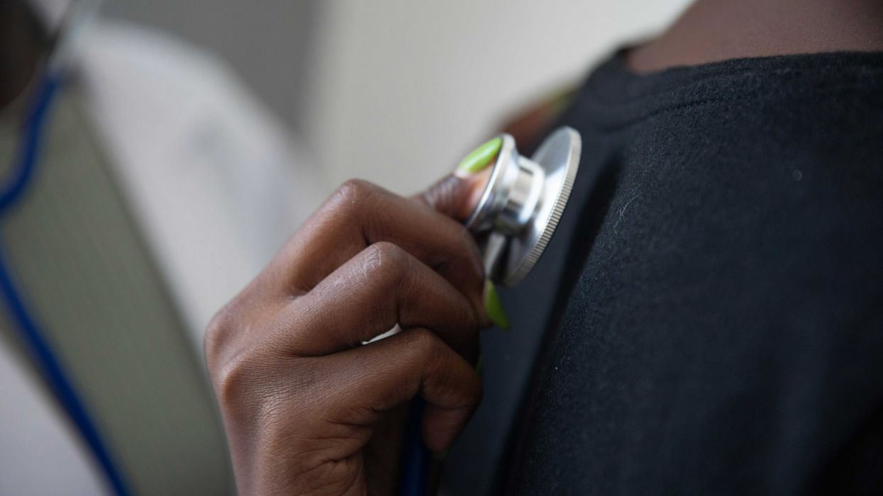 a doctor holding a stethoscope against another person's back.