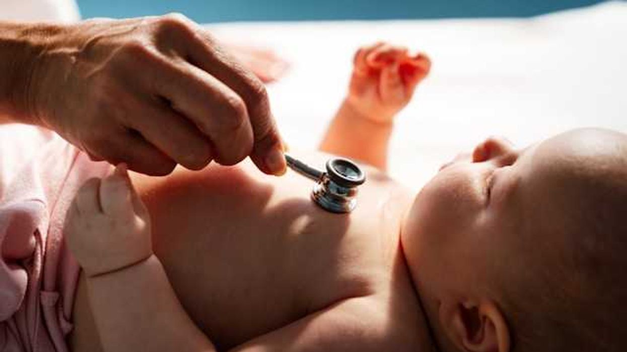 A doctor holding a stethoscope to a baby's chest