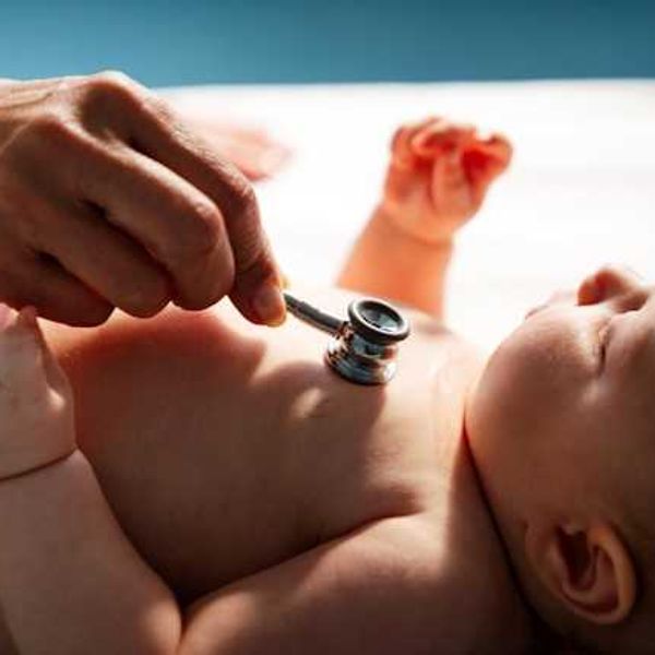A doctor holding a stethoscope to a baby's chest