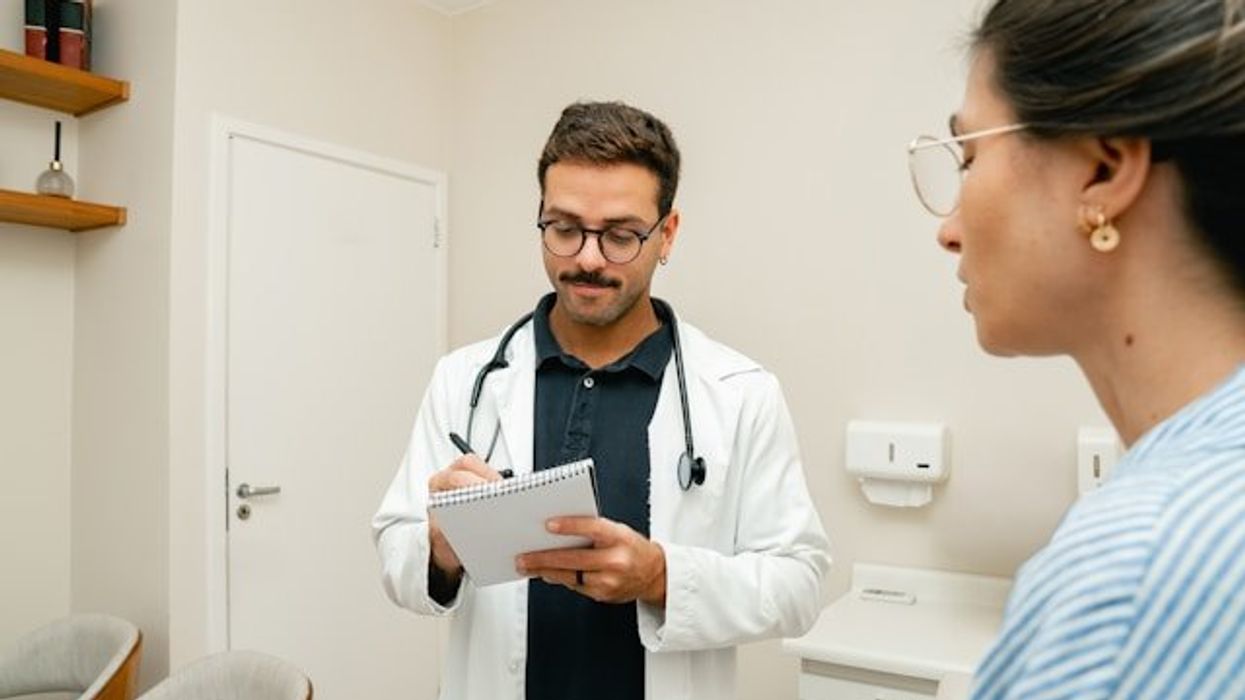 A doctor making notes during a patient interview with a young woman
