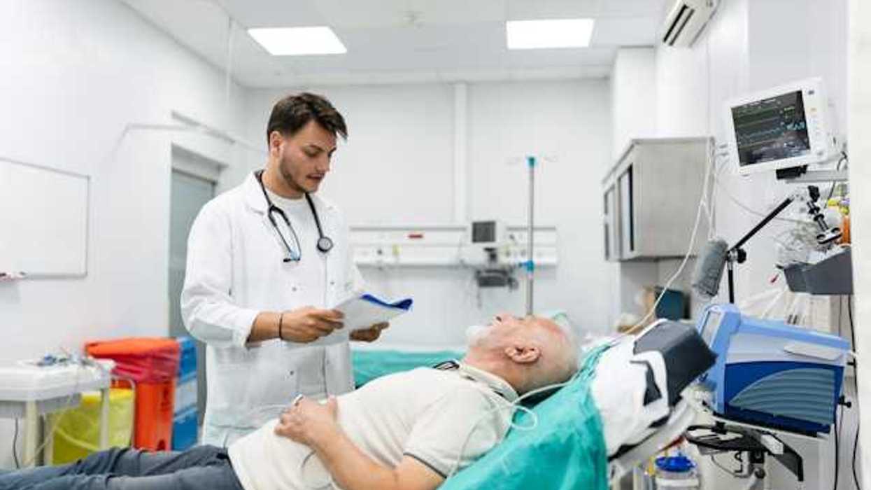 A doctor standing over a patient in an emergency room bed