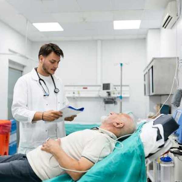 A doctor standing over a patient in an emergency room bed