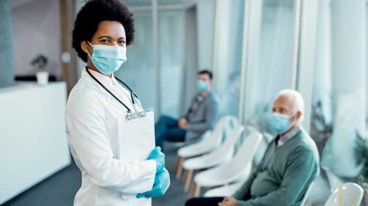 A doctor wearing a medical mask standing in front of patients in chairs
