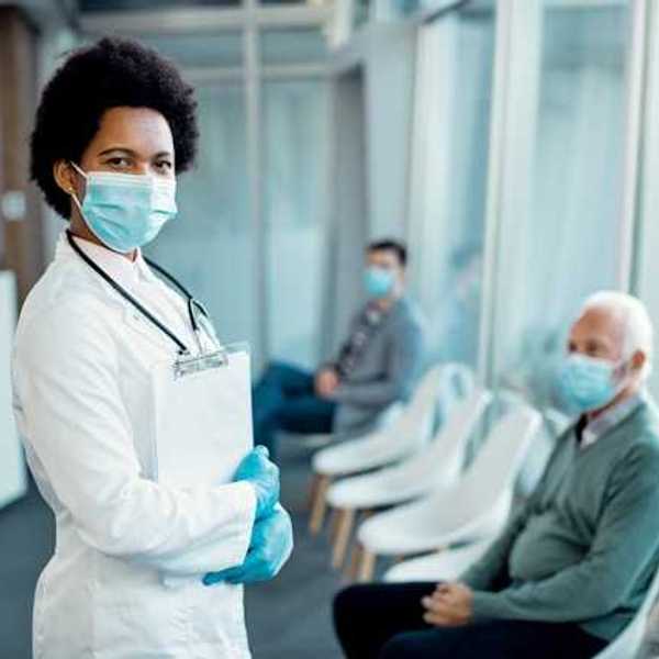A doctor wearing a medical mask standing in front of patients in chairs