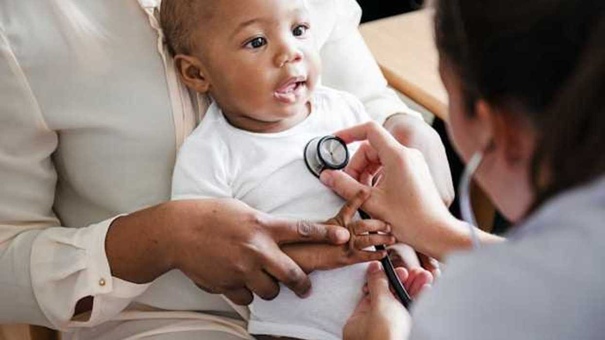 A doctor with a stethoscope against a small child's chest