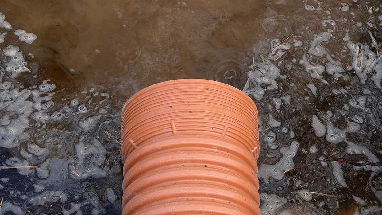 A drainage pipe emitting brown water into a river
