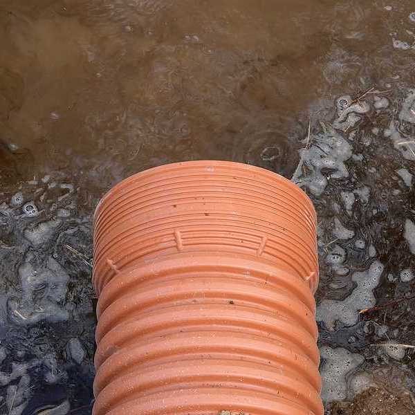 A drainage pipe emitting brown water into a river