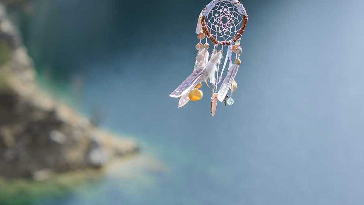 A dreamcatcher with feathers and twine with water in the background