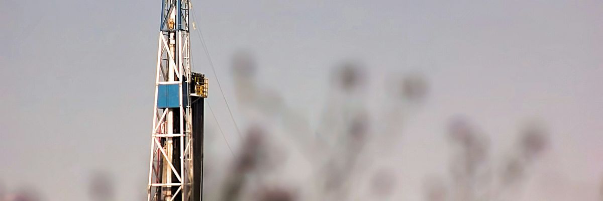 a drilling rig in a field with trees in the background