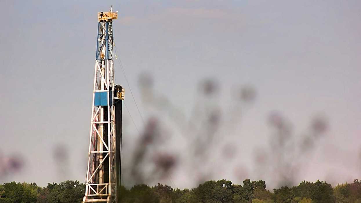 a drilling rig in a field with trees in the background.