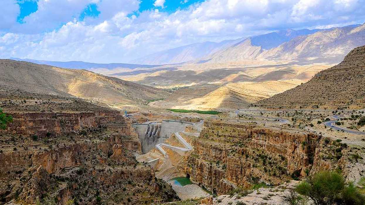 A dry environment with a dam and a small amount of water in view