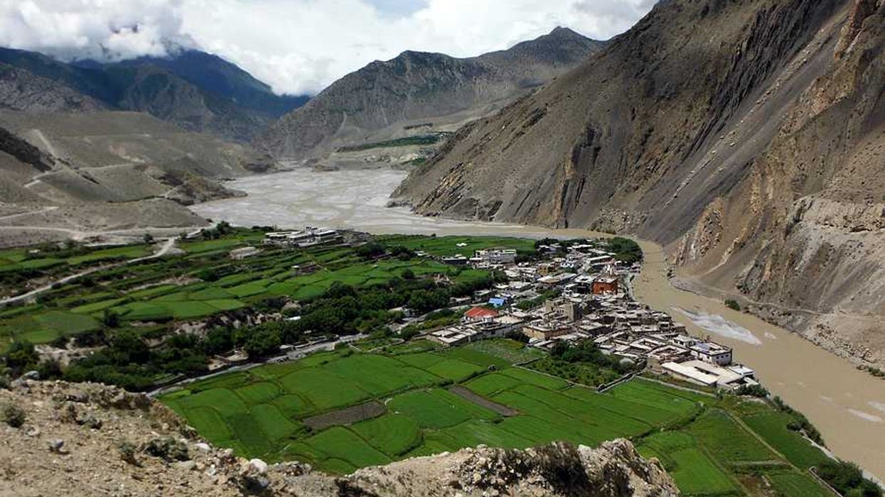 A dry river valley with a town surrounded by green fields