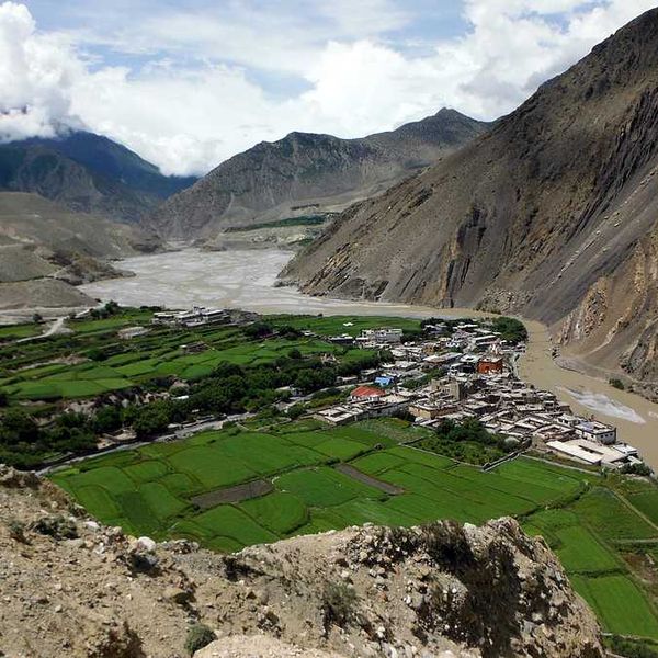 A dry river valley with a town surrounded by green fields