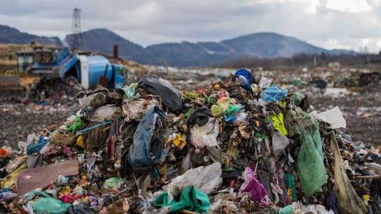 A dump site with trash piled up and mountains in the background