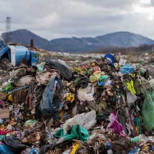 A dump site with trash piled up and mountains in the background