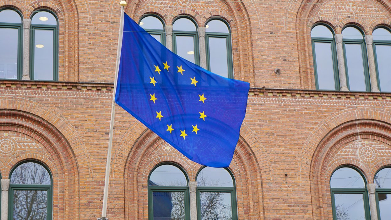 a european flag flying in front of a brick building