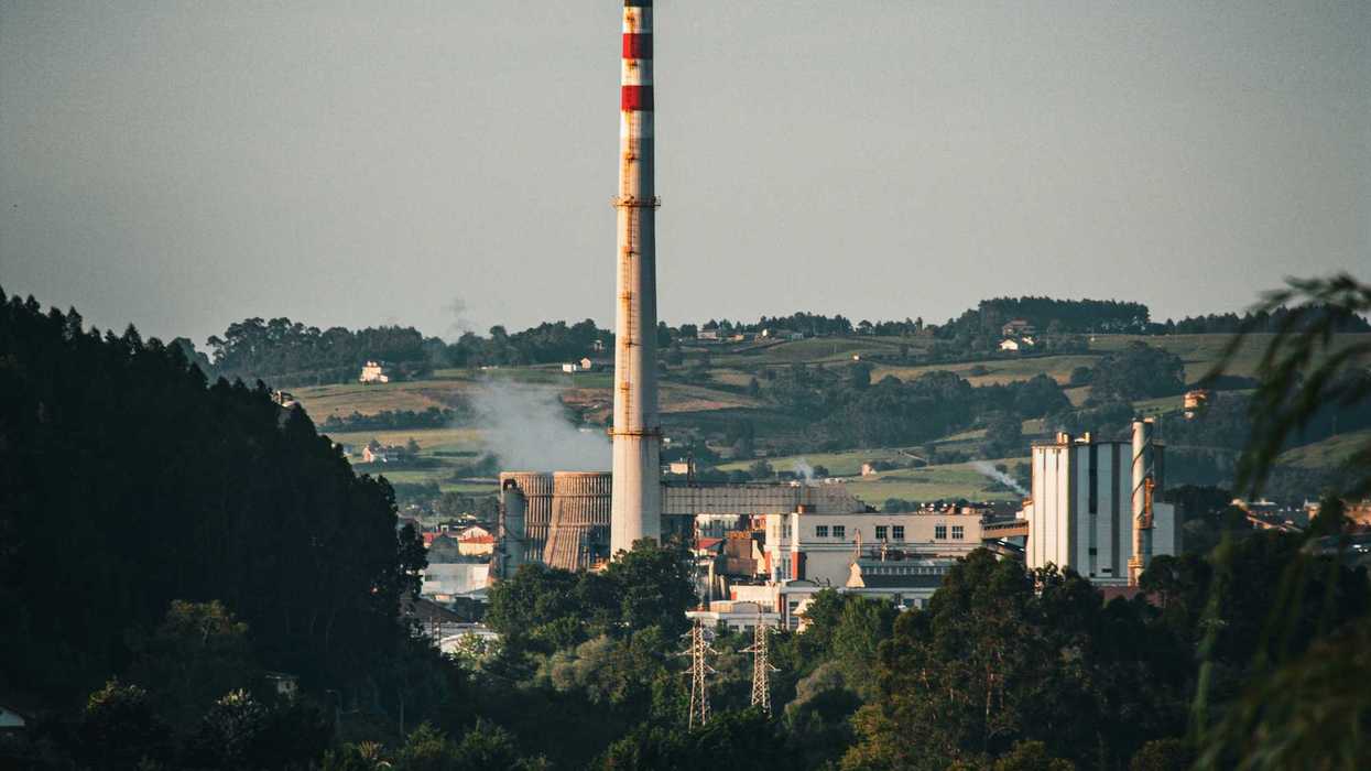 A factory or coal power plant with a smoke stack in the distance.