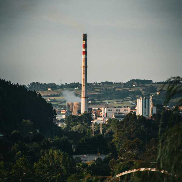 A factory or coal power plant with a smoke stack in the distance.
