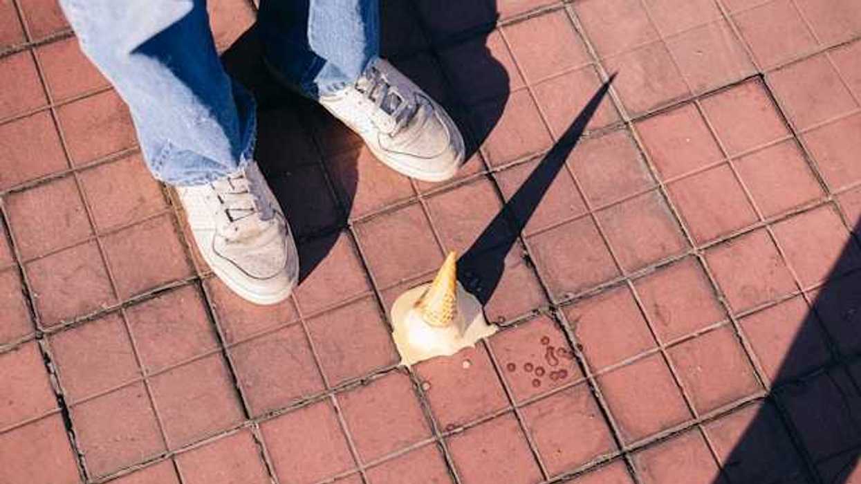 A fallen ice cream cone melting on the sidewalk