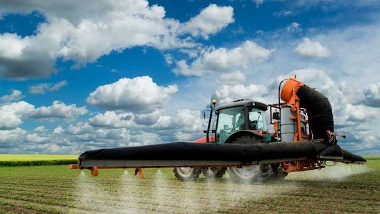 A farm combine spreading pesticides on a field