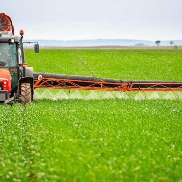 A farm tractor applying herbicide to a field