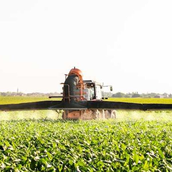 A farm tractor applying pesticides to a farm field