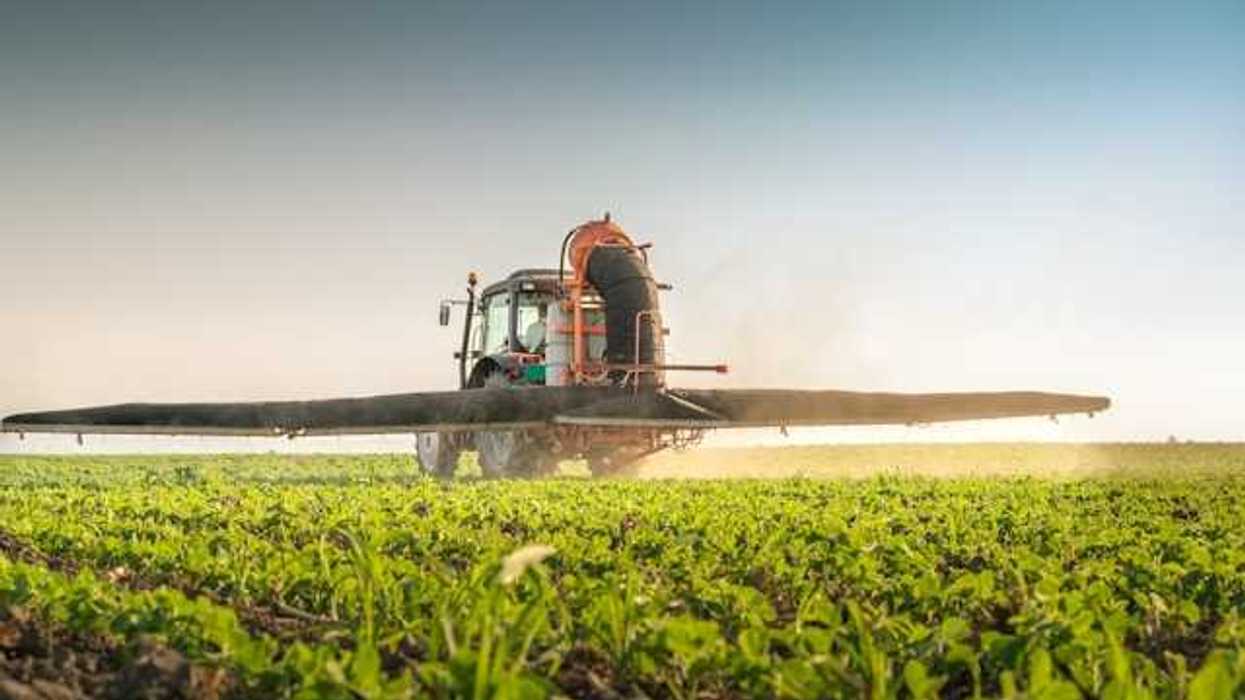A farm tractor applying pesticides to a field