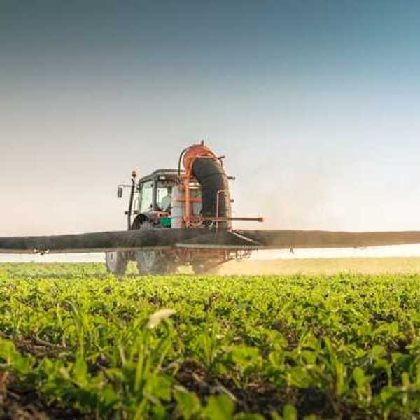 A farm tractor applying pesticides to a field