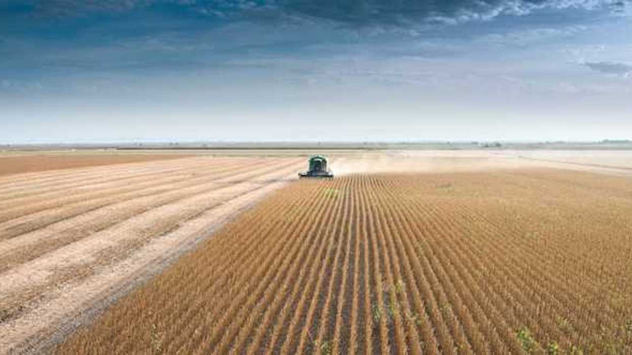 A farm tractor driving across a dry field