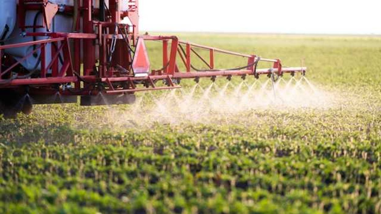 A farm tractor spraying pesticide on a field