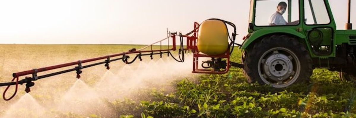 A farm tractor spraying pesticides on a farm field.