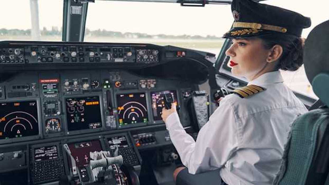 A female airplane pilot sitting at the controls of a jet airplane