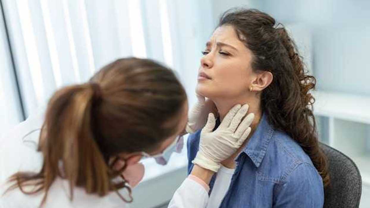 A female doctor with gloves on touching the neck of a female patient