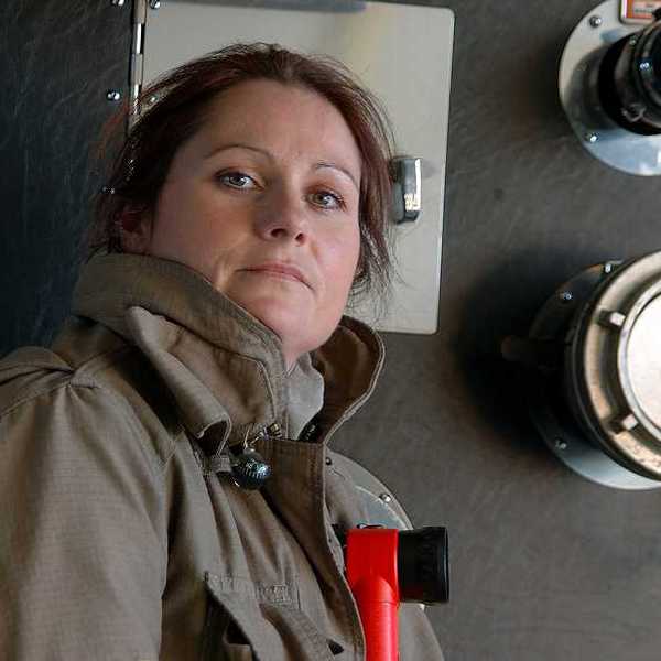A female firefighter standing next to a fire engine