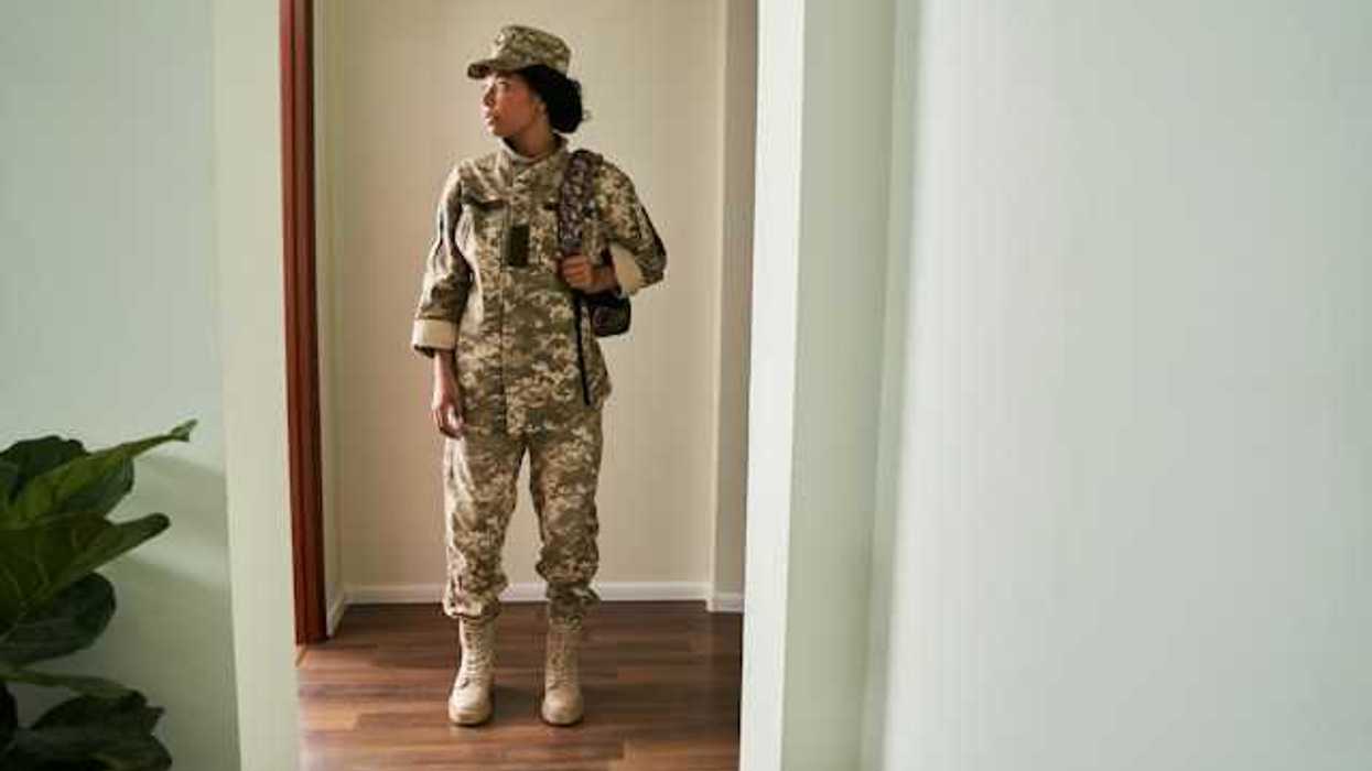 A female soldier in fatigues standing in a doorway