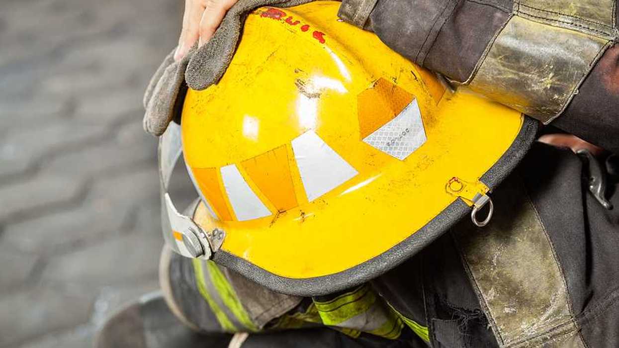 A firefighter holding a yellow hard hat