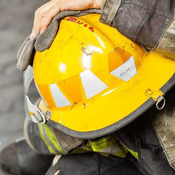 A firefighter holding a yellow hard hat