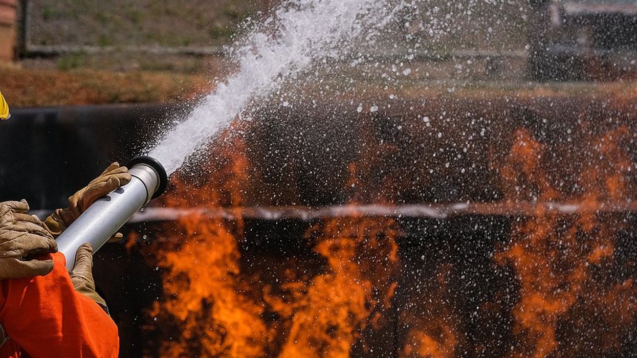 A firefighter spraying foam on a fire
