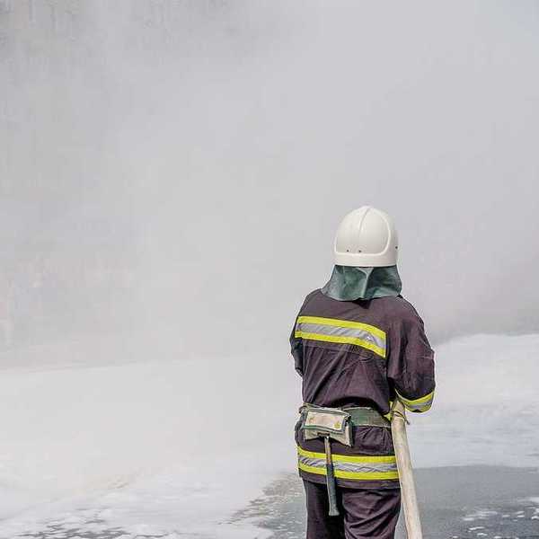 A firefighter spraying foam on the pavement