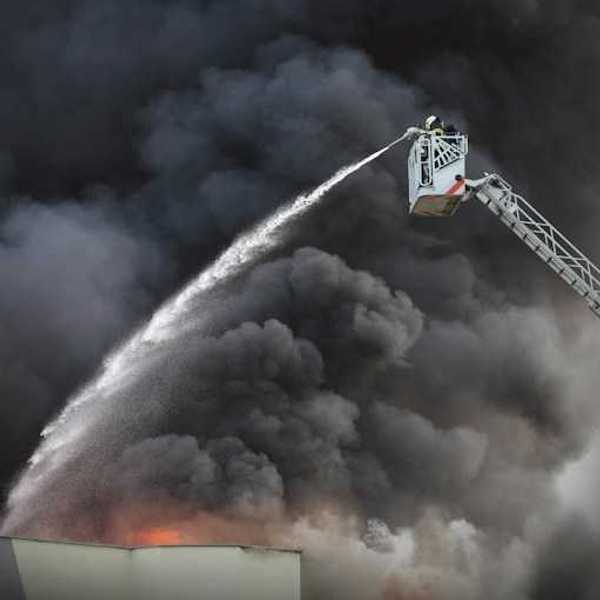 A firefighter spraying water from the air on a building fire