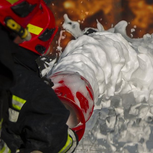 A firefighter spreading firefighting foam on flames