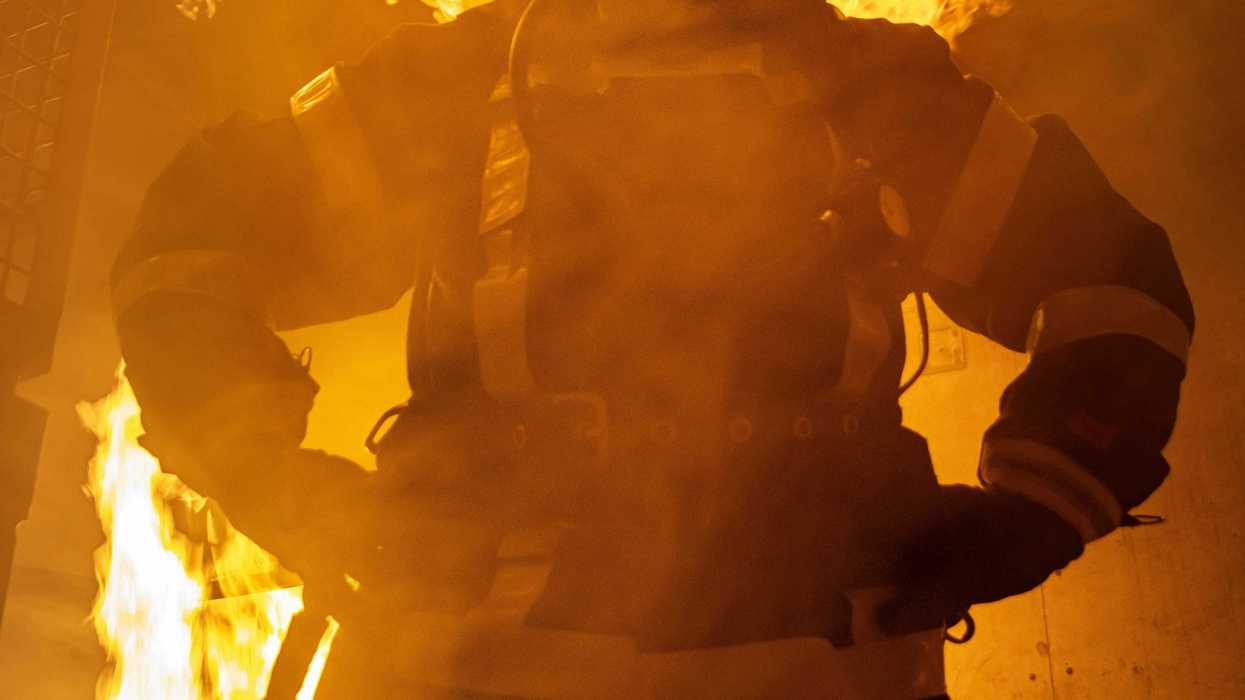 a firefighter standing in front of a large fire