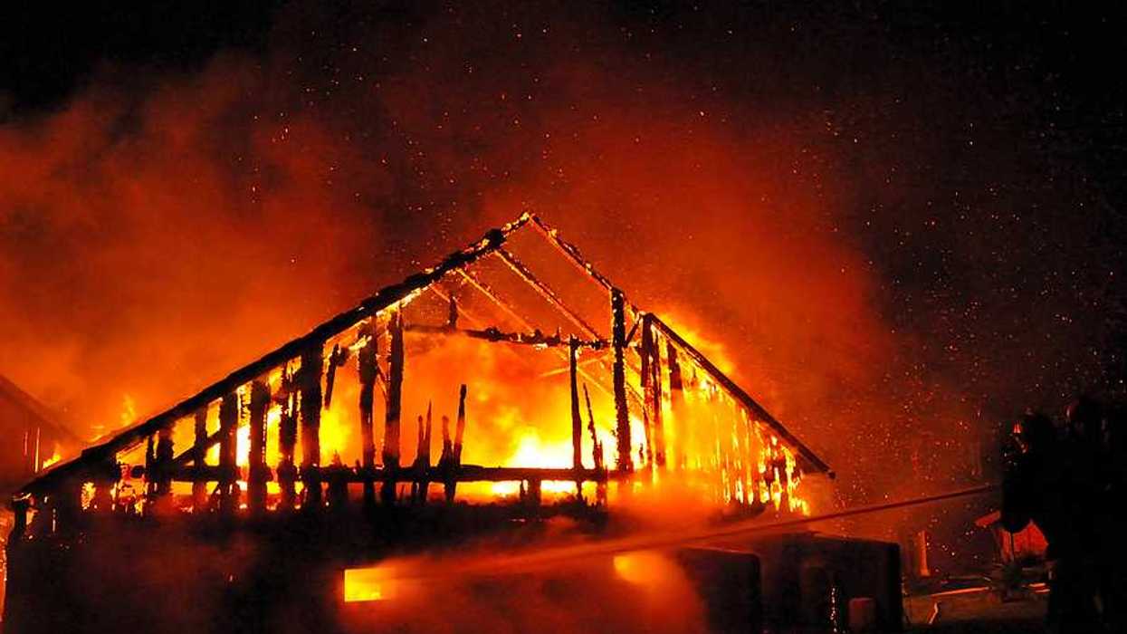 A fireman directs a water stream at a burning house