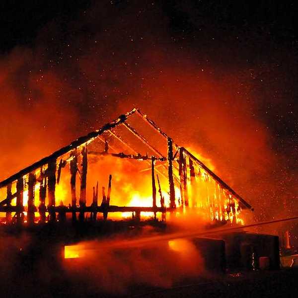 A fireman directs a water stream at a burning house