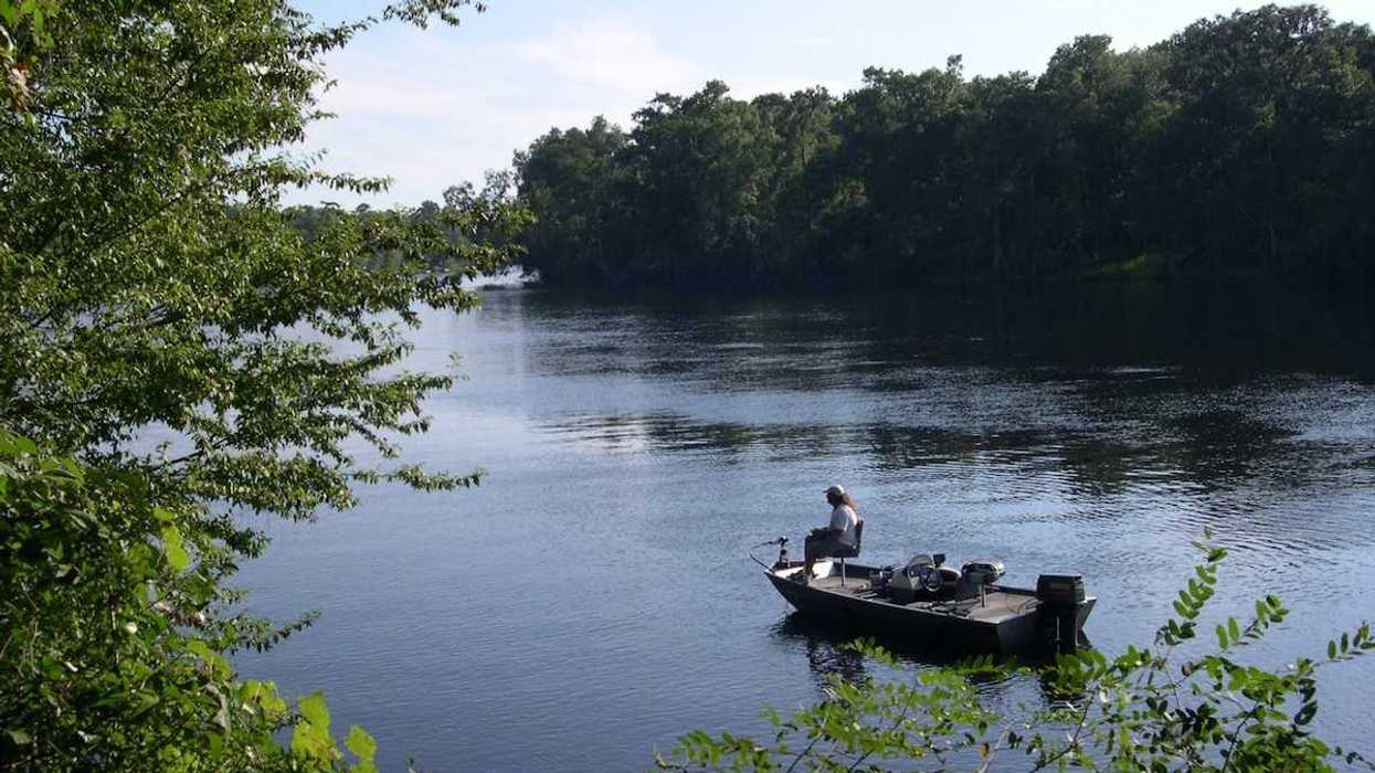 A fisherman slowly putters past the mouth of Hart Springs on the Suwannee river near Bell, Florida.