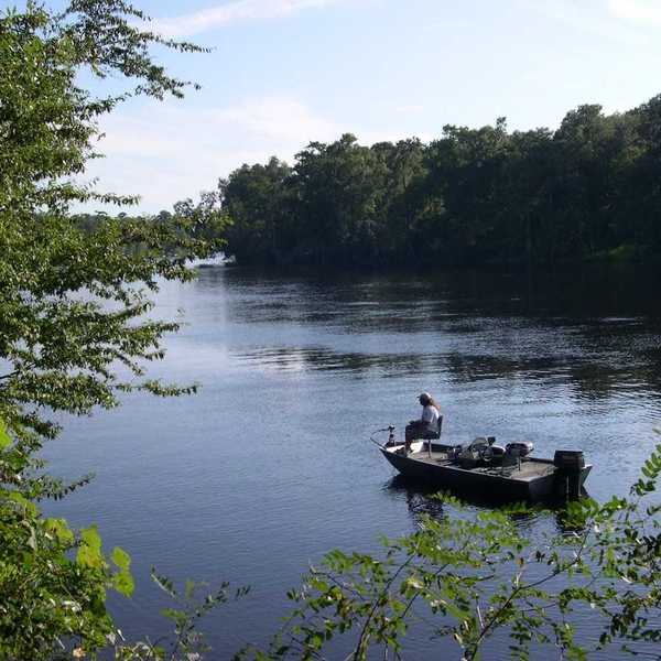 A fisherman slowly putters past the mouth of Hart Springs on the Suwannee river near Bell, Florida.