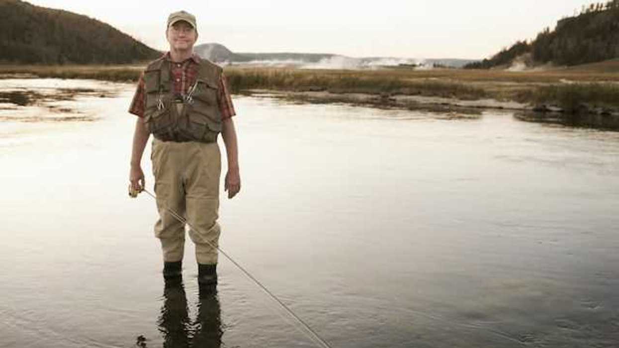 A fisherman standing in a shallow river