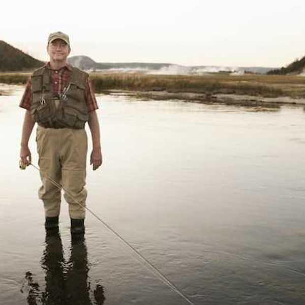 A fisherman standing in a shallow river