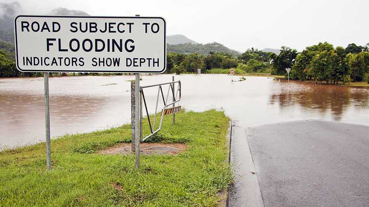 A flooded road with a sign indicating that the road is subject to flooding
