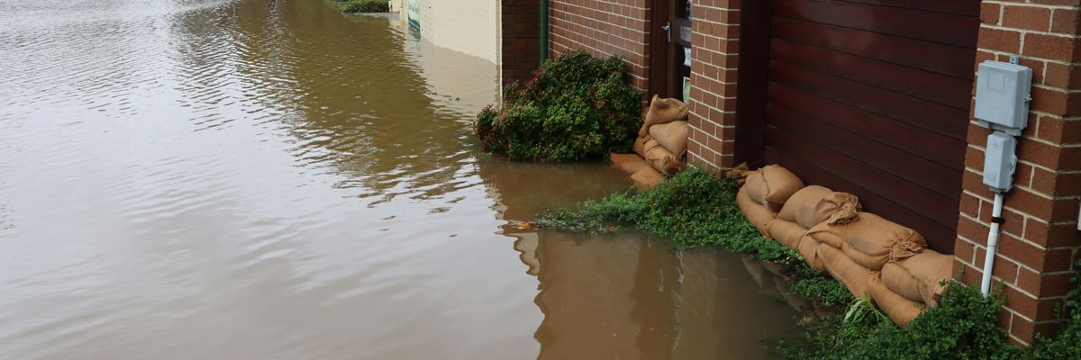 A flooded street with a building and sandbags protecting the doors.